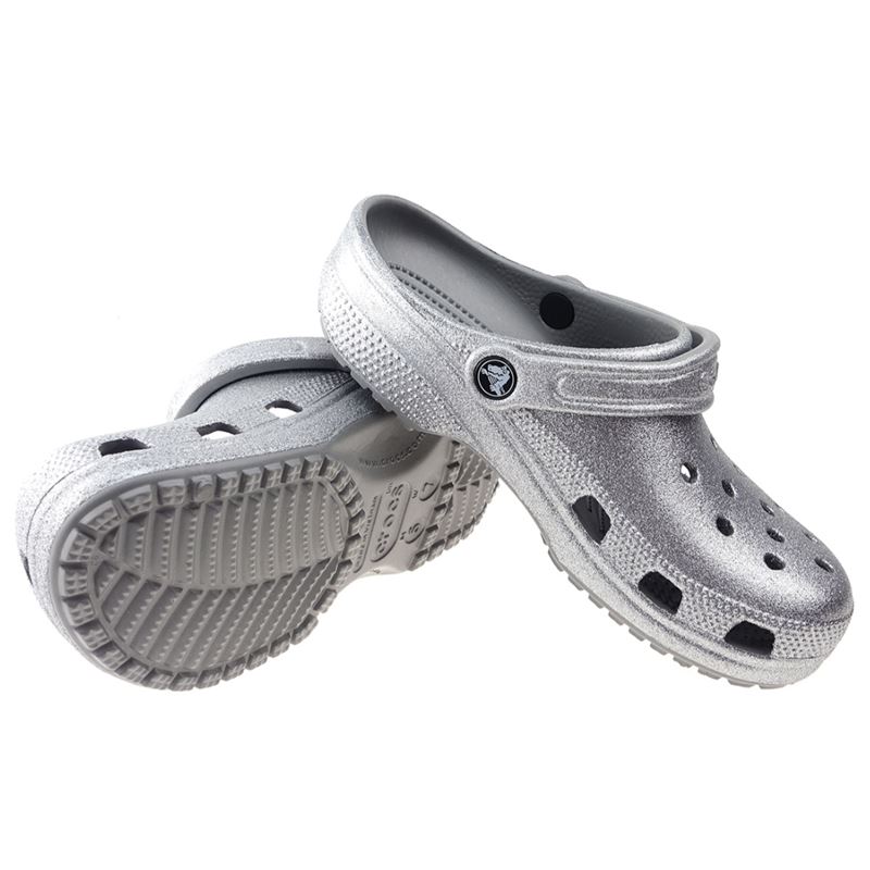 Crocs Classic Glitter Clog 205942 so udobni in lahki natikači z bleščečim glitter dizajnom, ki združujejo prepoznavno Crocs udobje in moderen, izrazit videz. Izdelani iz Croslite™ materiala zagotavljajo mehko blaženje, vodoodpornost in enostavno čiščenje, zato so primerni za vsakodnevno nošenje in modne kombinacije.