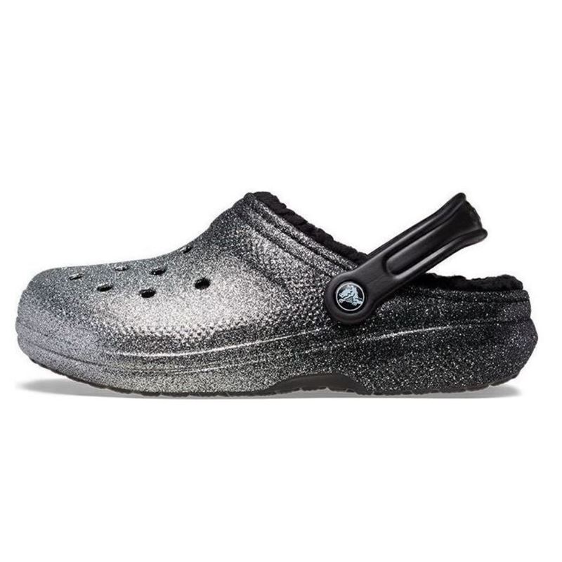 Bleščeči in udobni Crocs Classic Glitter Lined Clog – topli natikači z mehko notranjo podlogo in sijočim glitter dizajnom, ki združujejo udobje, toplino in moderen, igriv videz. Idealni za hladnejše dni doma ali na prostem, kjer želiš dodatno udobje in malo sijaja.