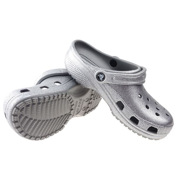Crocs Classic Glitter Clog 205942 so udobni in lahki natikači z bleščečim glitter dizajnom, ki združujejo prepoznavno Crocs udobje in moderen, izrazit videz. Izdelani iz Croslite™ materiala zagotavljajo mehko blaženje, vodoodpornost in enostavno čiščenje, zato so primerni za vsakodnevno nošenje in modne kombinacije.